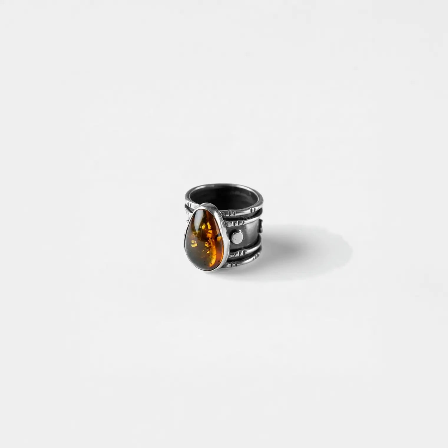 Silver ring with a amber stone on a white background