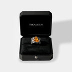 Silver ring with a yellow amber in a black Tikalkun jewelry box on a light gray background