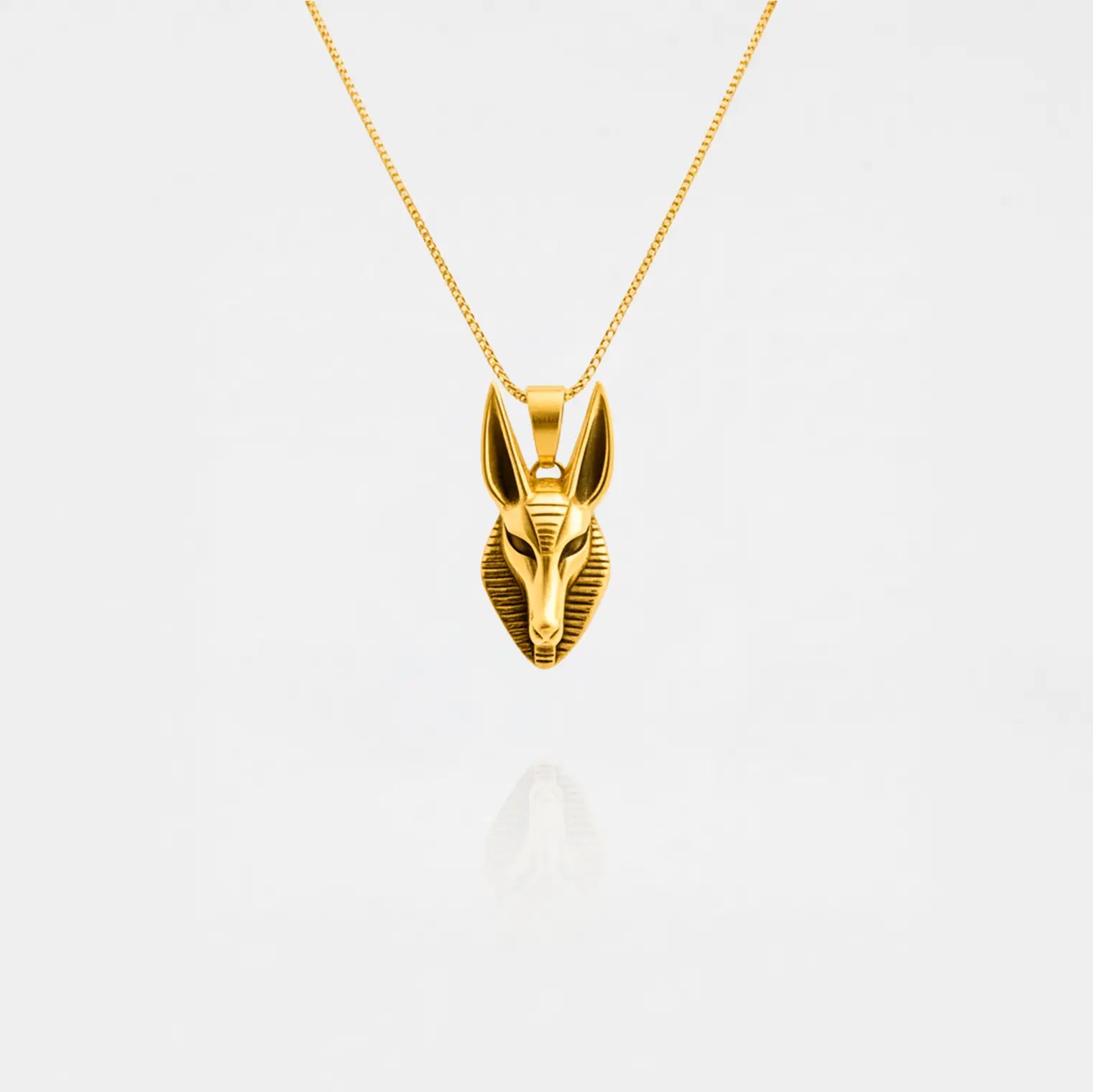 Gold Anubis pendant necklace on a white background
