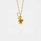 Gold axolotl-shaped pendant on a chain against a white background