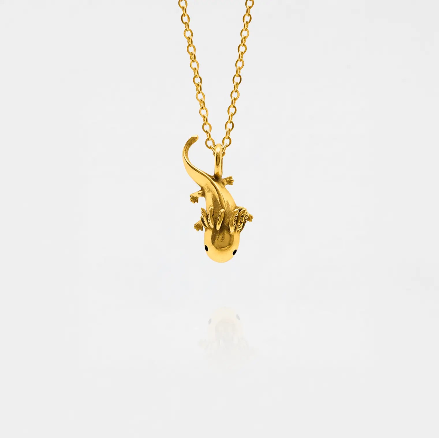 Gold axolotl-shaped pendant on a chain against a white background