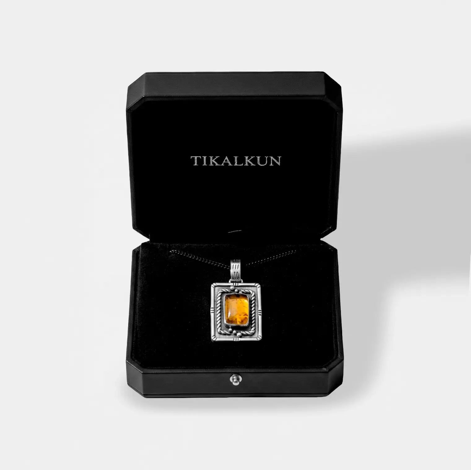 Jewelry box with a pendant featuring an amber gemstone and 'TIKALKUN' branding.