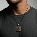 Man wearing a dark gray shirt with a necklace featuring a rectangular pendant.
