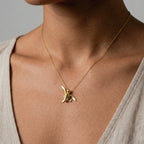 woman wearing a baby turtle gold pendant on a white background