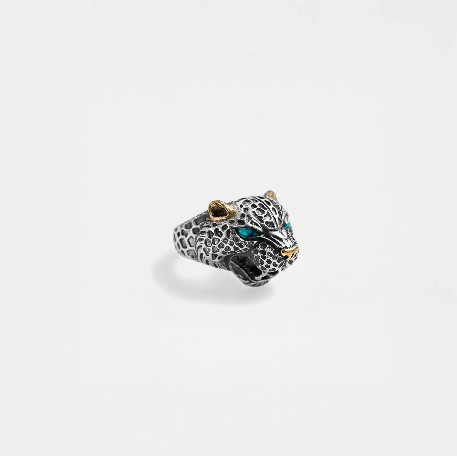 Jaguar head ring with gold accents and turquoise stones on a light gray background