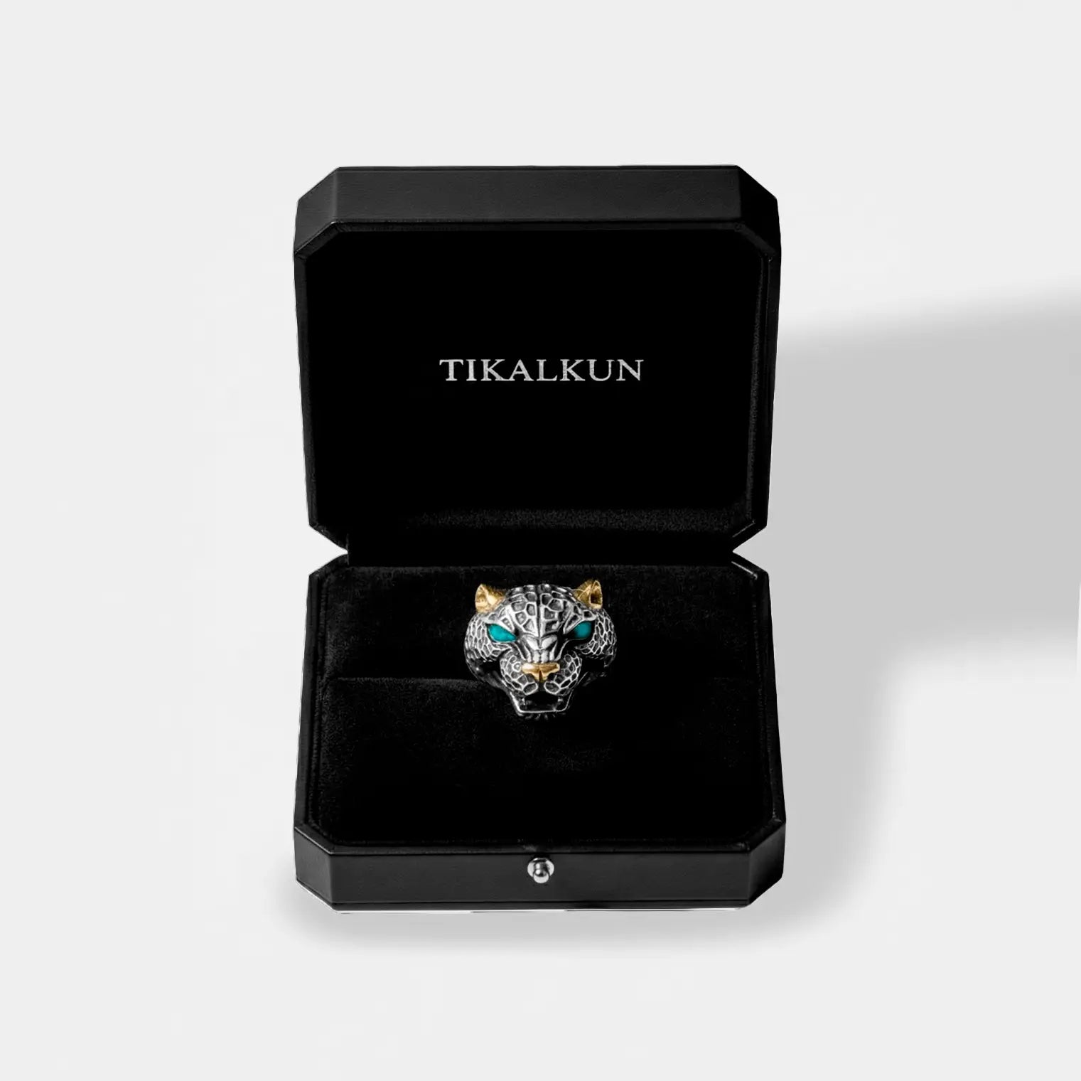 Silver jaguar ring with turquoise eyes in a black Tikalkun box on a light gray background