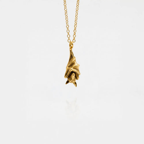 Gold bat pendant necklace on a white background