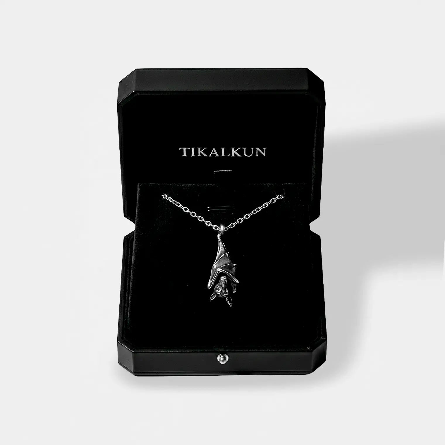 Silver necklace with a bat pendant on a black Tikalkun jewelry box against a white background