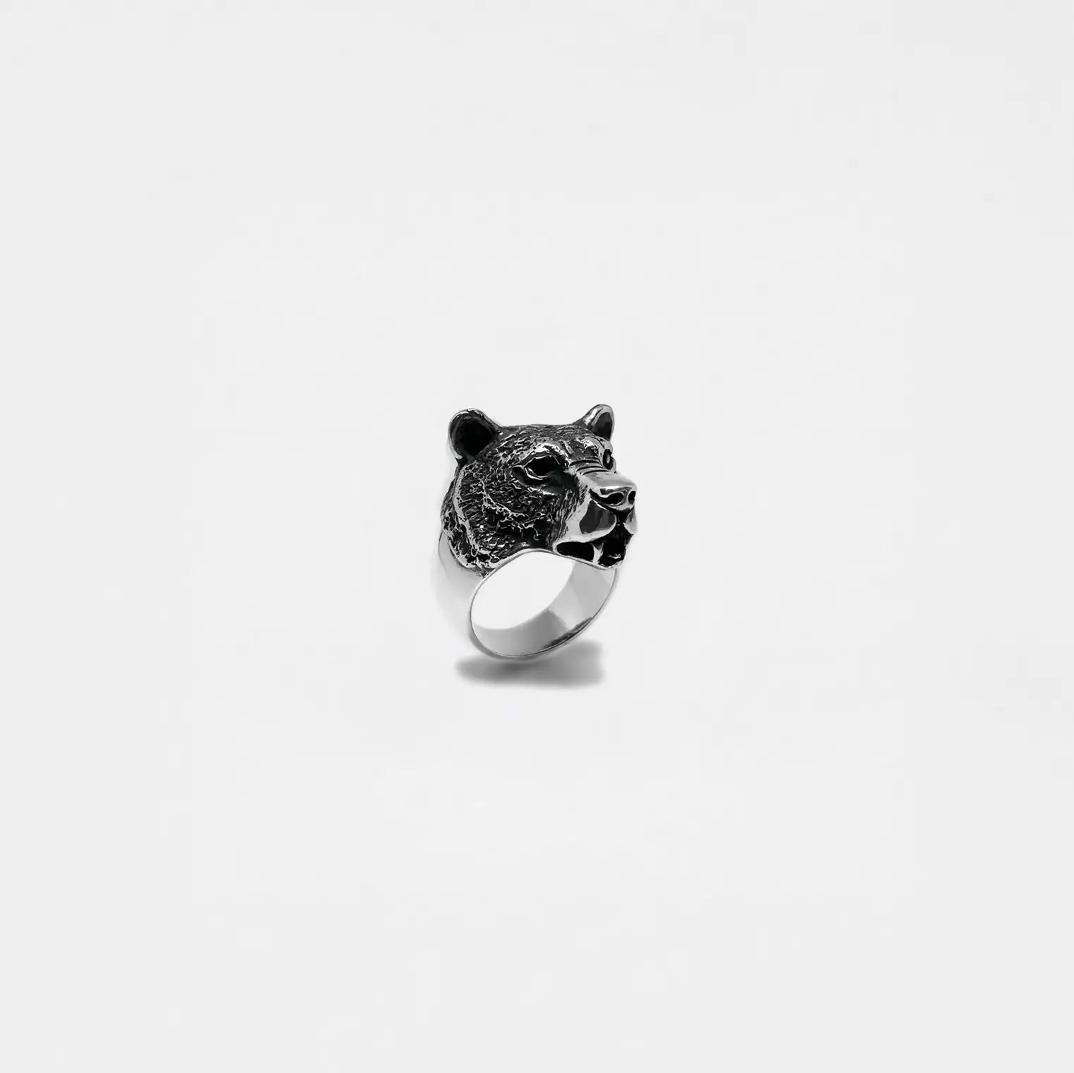 Silver ring with a bear head design on a white background