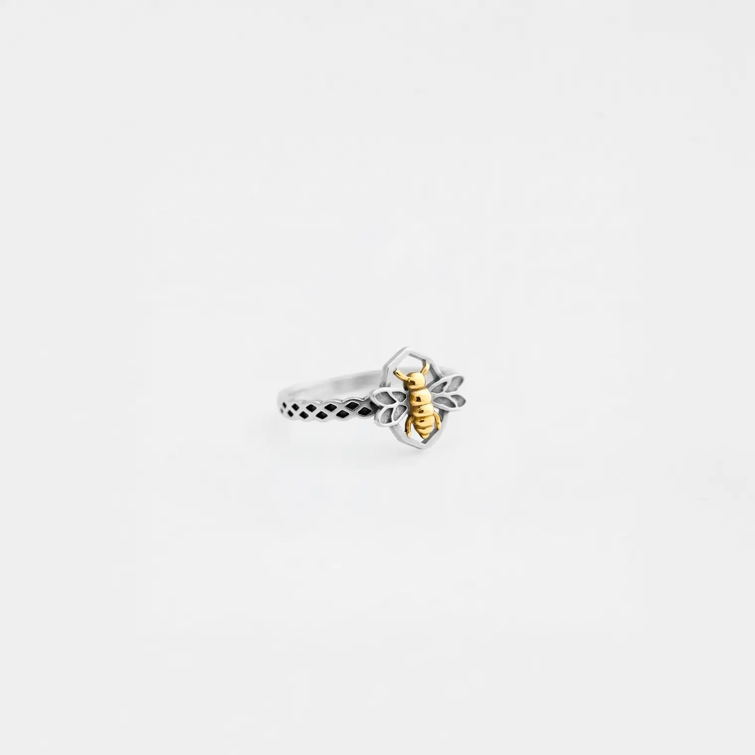 Silver bee ring with a gold bee design on a white background