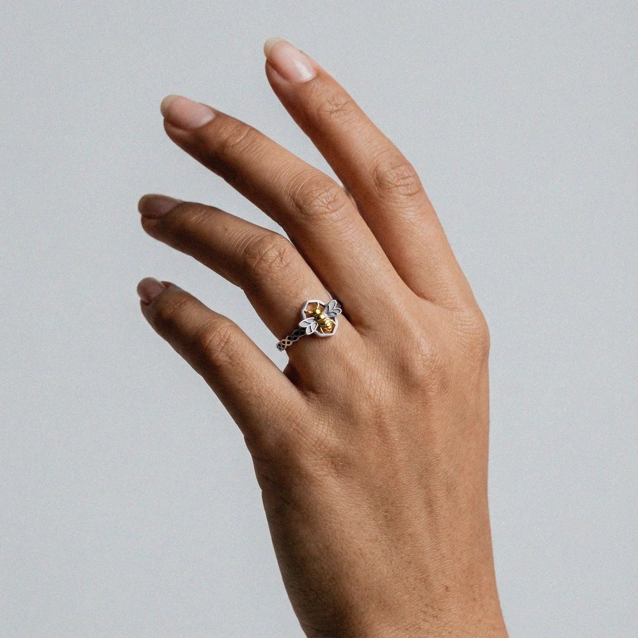 Hand wearing a bee silver ring with gold plate