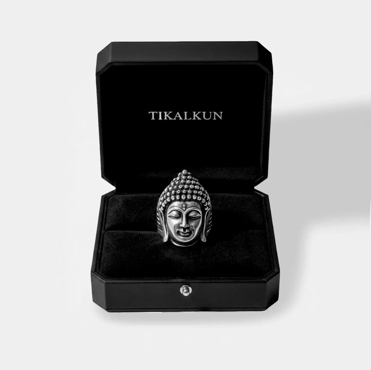 Silver Buddha head ring in a black Tikalkun jewelry box on a light gray background