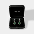 Green cactus earrings in a black Tikalkun jewelry box on a light gray background