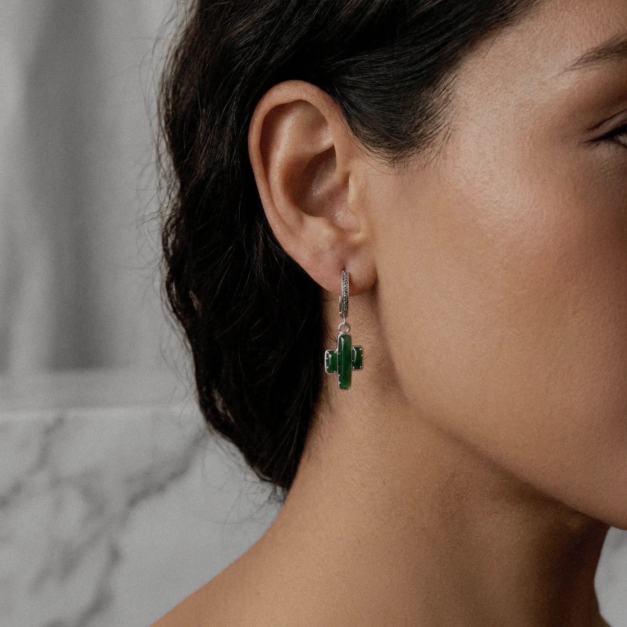 Close-up of a woman wearing a green cactus-shaped earring.