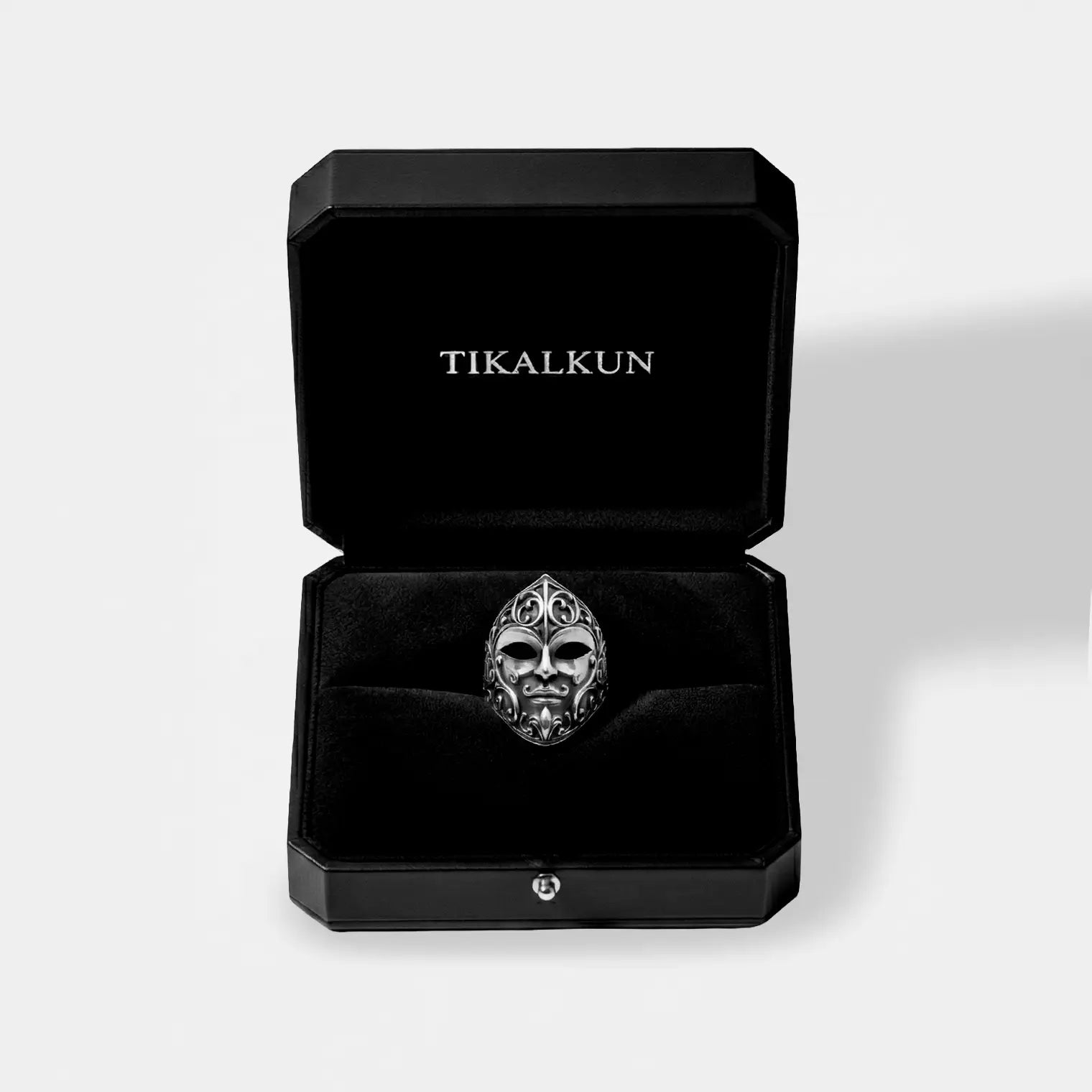 Black jewelry box with a carnival mask silver ring on a light gray background