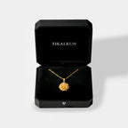 marigold flower Gold necklace in a black Tikalkun jewelry box on a light gray background