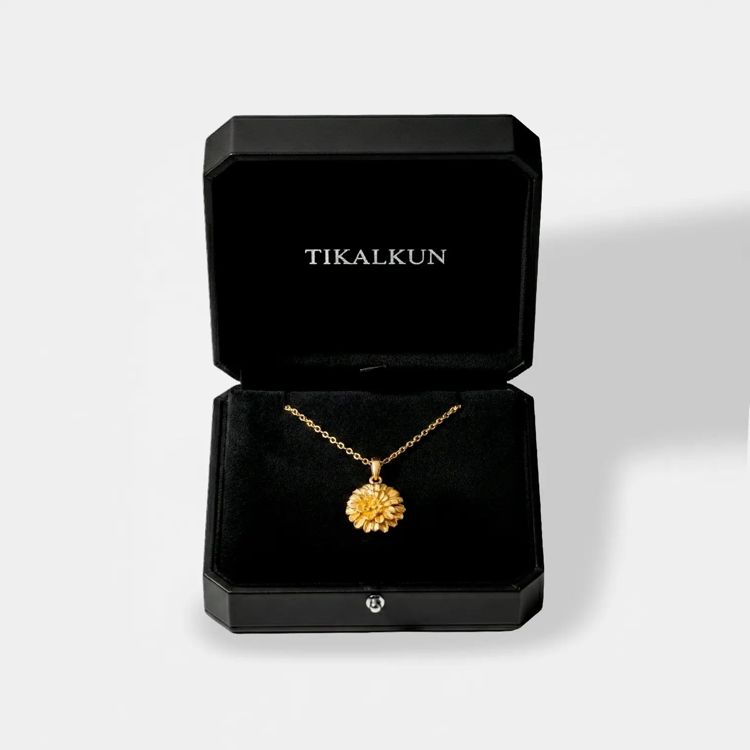 marigold flower Gold necklace in a black Tikalkun jewelry box on a light gray background