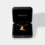 black "TIKALKUN" jewelry box with a gold cowboy boot pendant isnide it,  on a white background