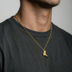 person wearing a gold cowboy boot pendant on a gray background