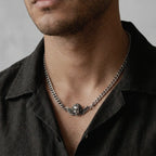 person wearing a silver necklace featuring a cherub design 