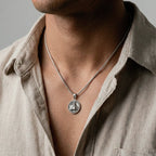 Necklace with a pyramid pendant worn by a person in a beige shirt against a neutral background