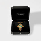 aztec shield Gold necklace with turquoise stones in a black 'TIKALKUN' box on a light gray background