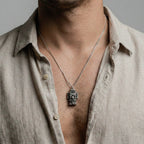 Man wearing a coatlicue silver pendant on a gray background