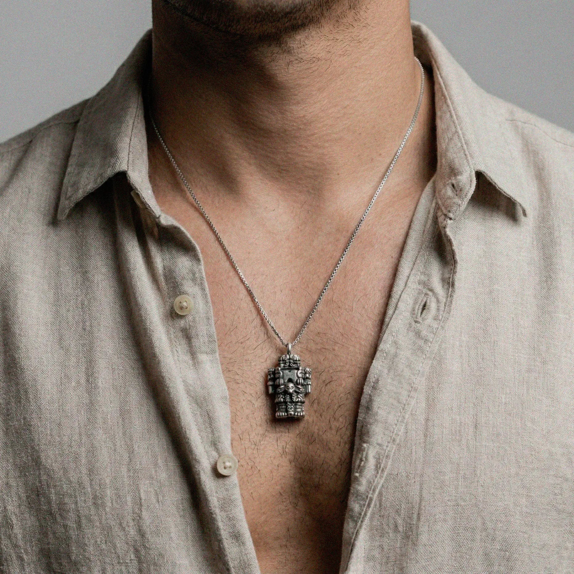 Man wearing a coatlicue silver pendant on a gray background