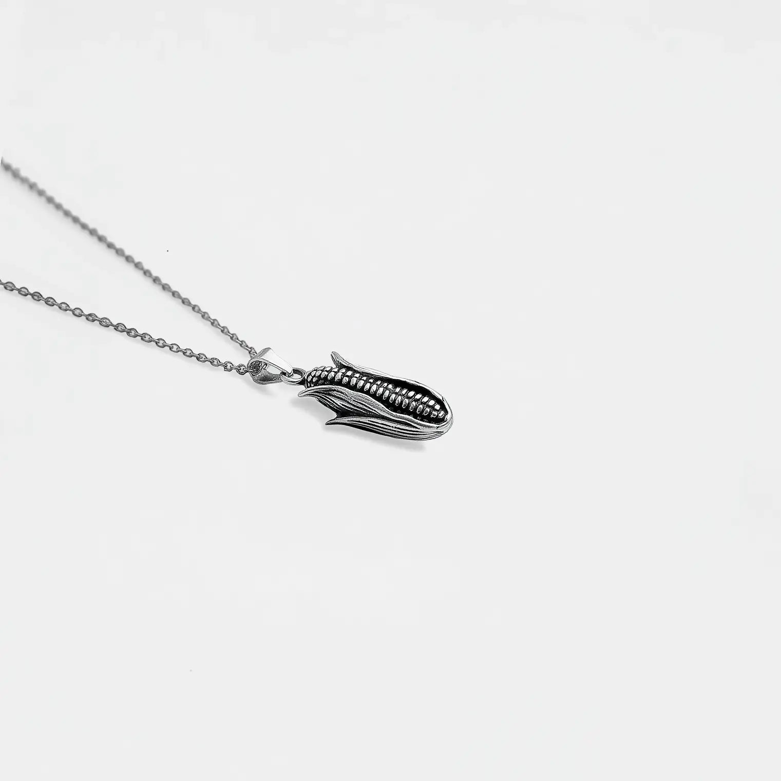 Silver necklace with a unique corn on a light gray background