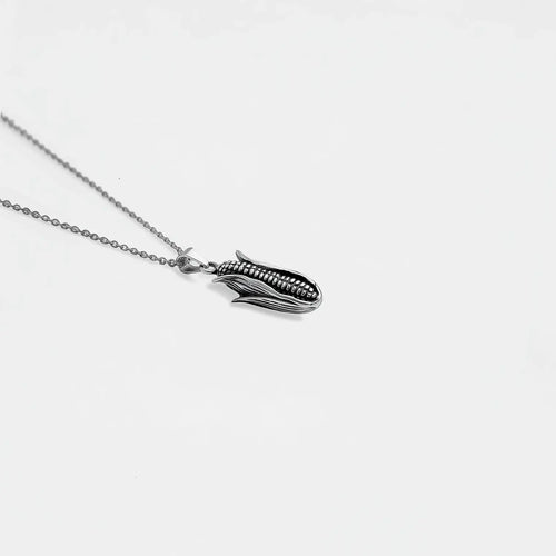 Silver necklace with a unique corn on a light gray background