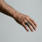 Hand wearing a corn cob ring on a plain background