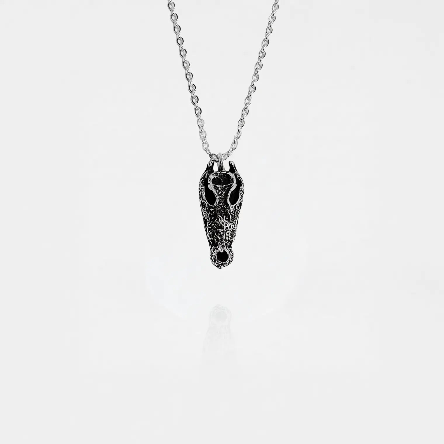 Silver necklace with a crocodile skull pendant on a white background