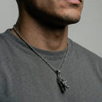 Man wearing a necklace with a crocodile pendant on a plain background
