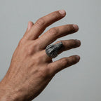 Hand wearing a crocodile silver ring on a plain background