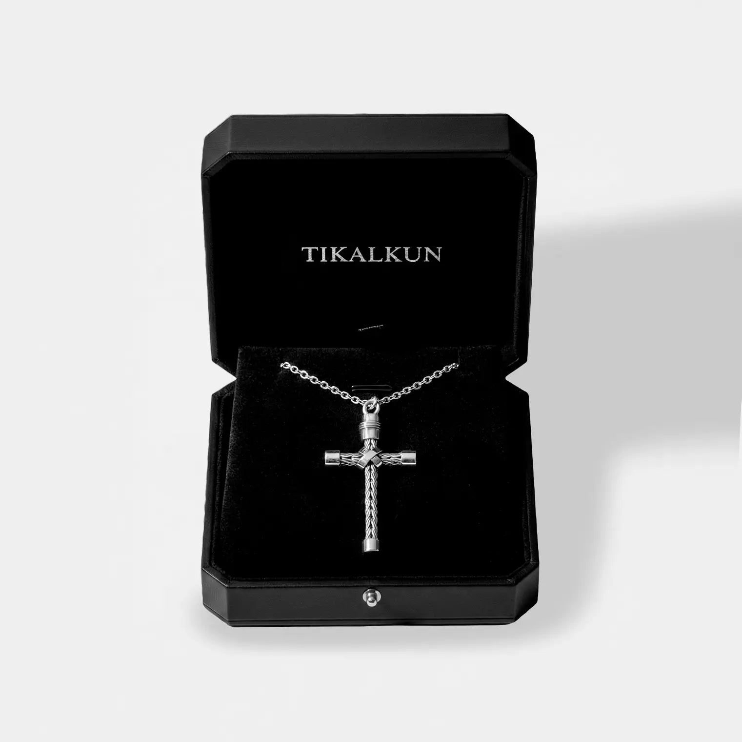 Silver cross necklace in a black Tikalkun jewelry box on a light gray background