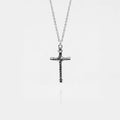 Silver cross pendant on a chain against a white background