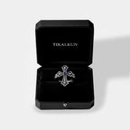 black "TIKALKUN" jewlry box with a Silver cross ring with gemstone on a white background