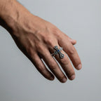 man's hand wearing a Silver cross ring with gemstone on a gray background