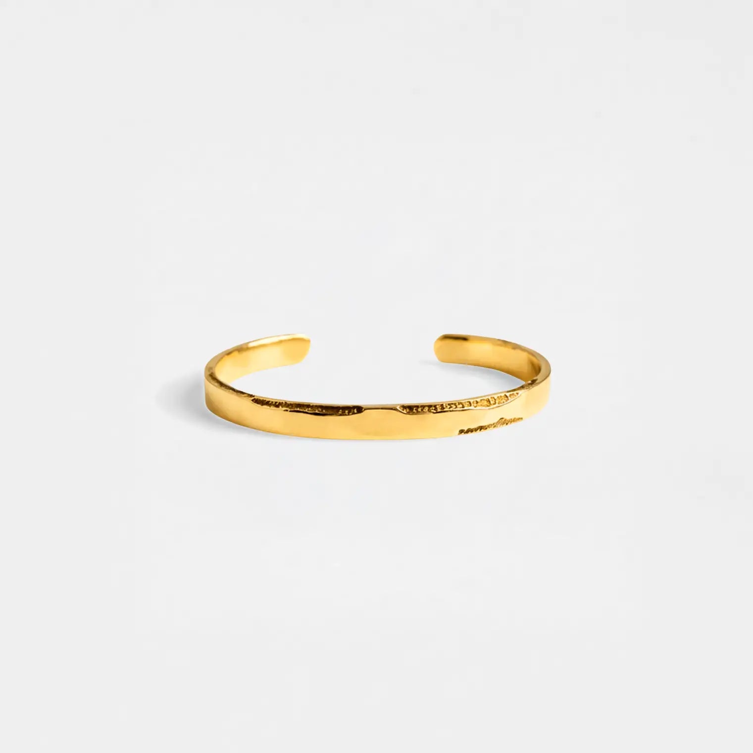Gold bracelet on a light gray background