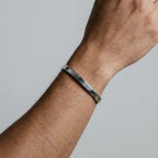 Silver bracelet on a wrist against a neutral background