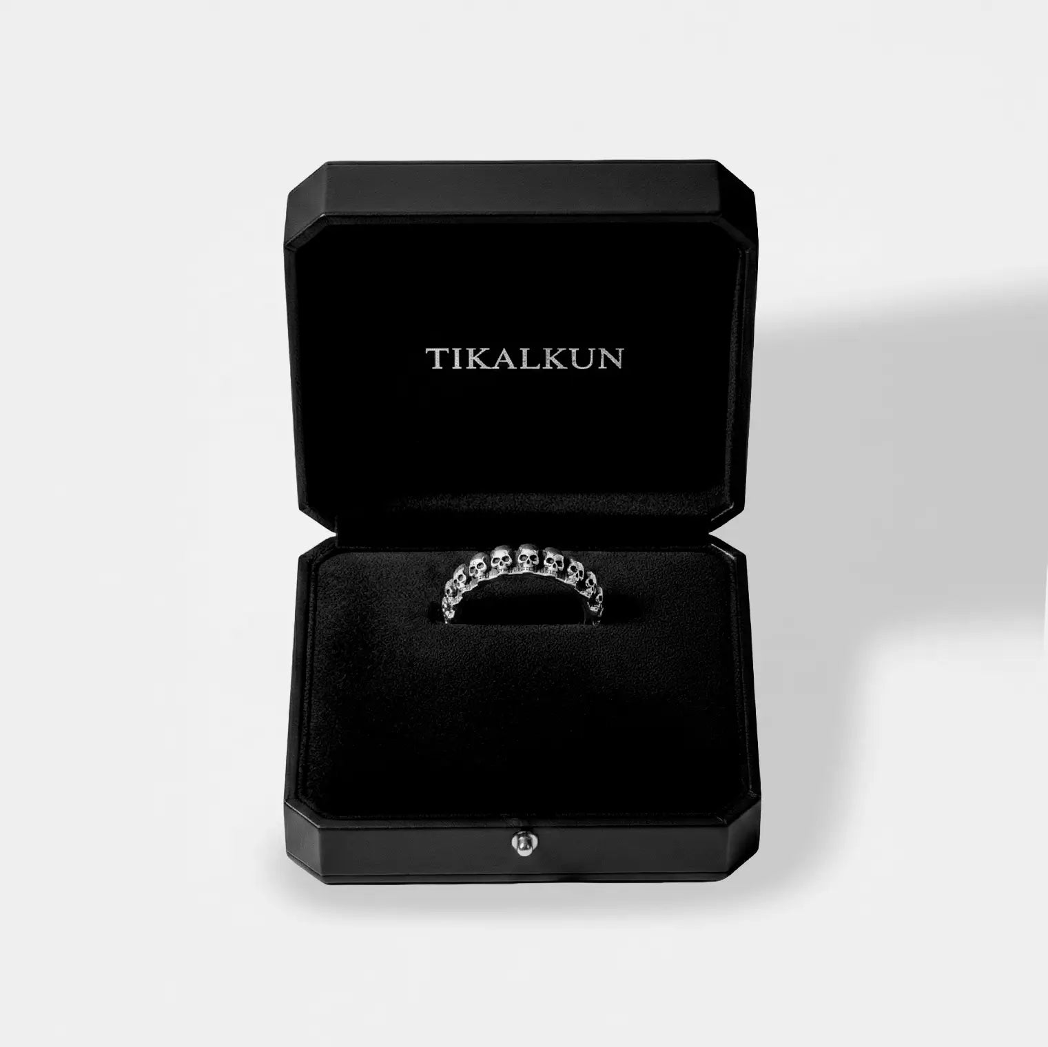 Silver skulls ring in a black Tikalkun jewelry box on a light gray background