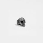 Silver skull ring with intricate designs on a light gray background
