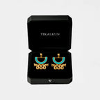 Gold and turquoise aztec earrings in a black Tikalkun box on a light gray background