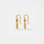 Gold aztec earrings with turquoise stones on a light gray background