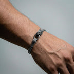 Silver chain bracelet on a wrist against a gray background
