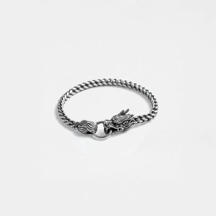 Silver chain bracelet with dragon clasp on a light gray background