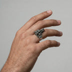 Hand wearing a silver ring with a DRAGON design on a plain background