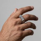 Hand wearing a silver ring with egyptian text on a gray background