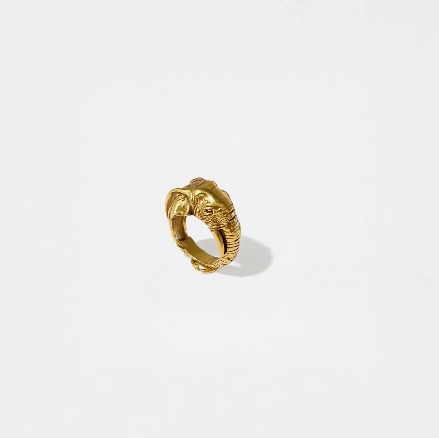 Gold elephant ring on a light gray background