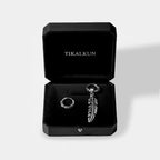 Silver earring with feather design in a black Tikalkun box on a light gray background